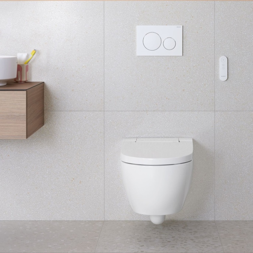 Product lifestyle image of Geberit Aquaclean Alba Wall Hung Smart Bidet Toilet 146.350.01.1 - front angle, large off white tiled bathroom